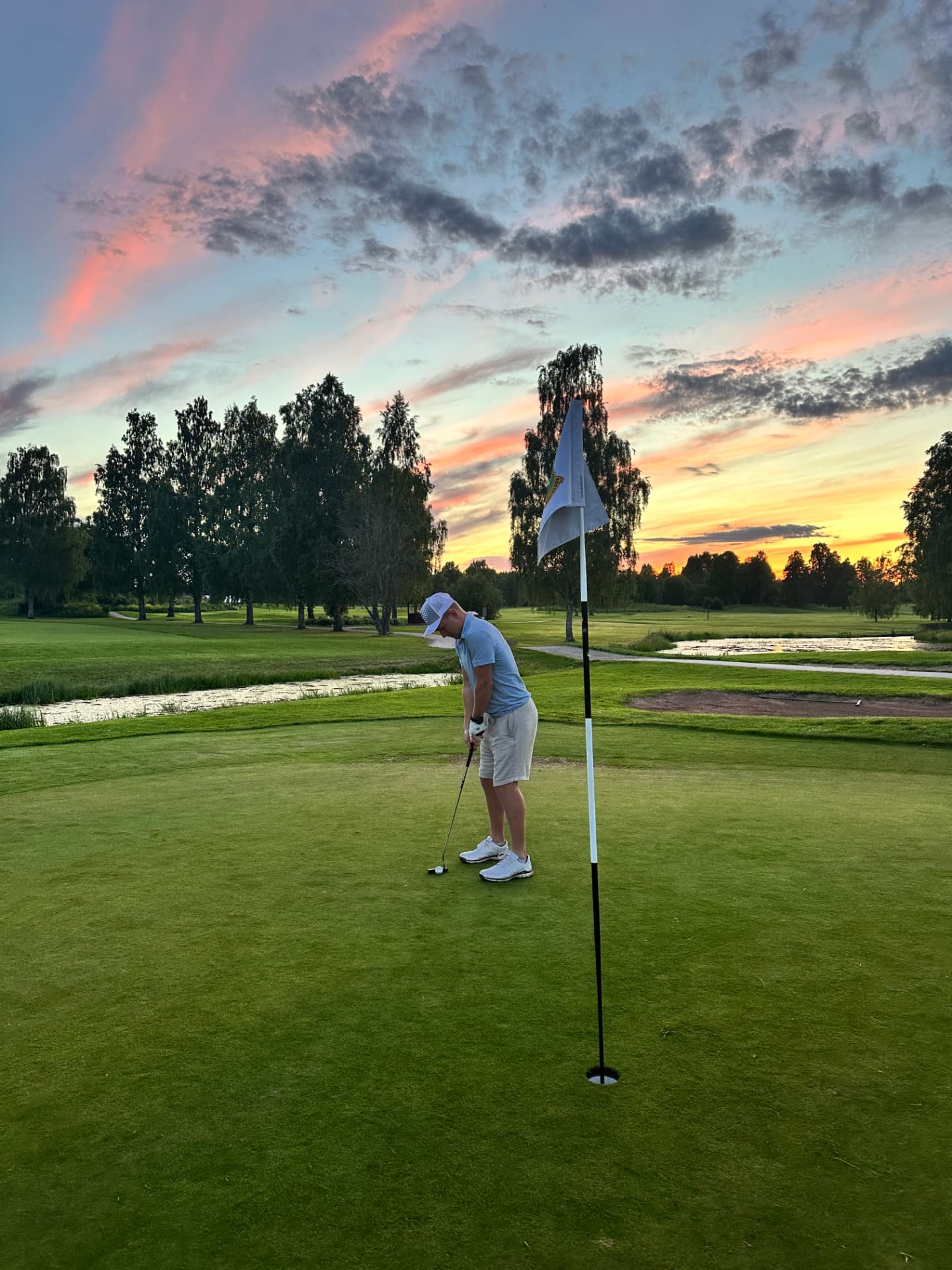 Golfare på green i solnedgång